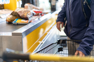 A man waits for a queue to pays for purchases at the cash desk in supermarket.