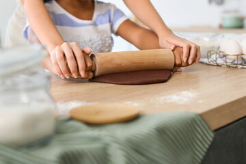 Obraz na płótnie Canvas African-American little girl and her mother rolling out dough in kitchen