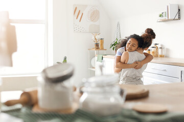 Obraz na płótnie Canvas African-American little girl hugging her mother in kitchen