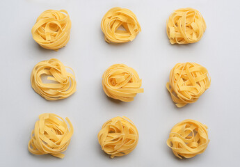 Uncooked tagliatelle pasta on light background