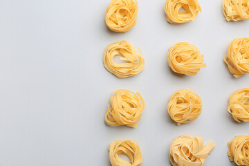 Uncooked tagliatelle pasta on light background