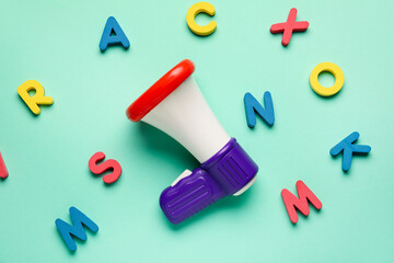 Toy megaphone with letters on color background