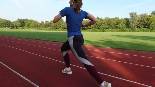Young woman in sports wear running fast sprint on stadium. 60fps 4K footage