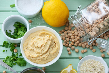 Bowl with tasty hummus and ingredients on color wooden background