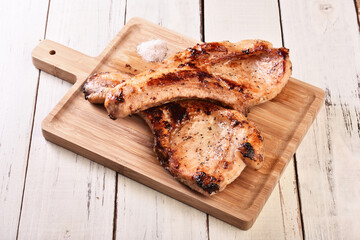 Two grilled tomahawk pork chops on wooden board 