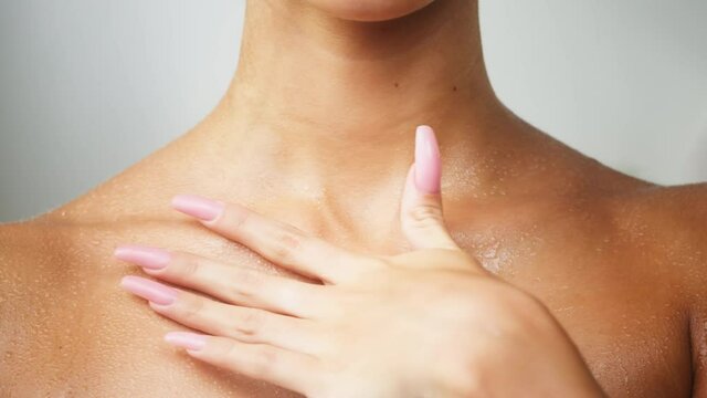 Young woman touching wet clavicles close-up, model with smooth skin after shower. Female shoulders, naked body. Beauty and body care concept. Unrecognizable person with bare neck and chest. 