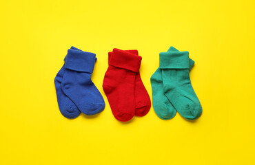 Different baby socks on color background