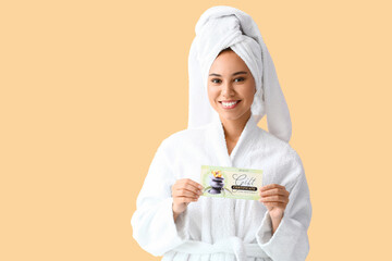 Young African-American woman with gift certificate for massage on color background