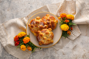 Plate with bread of the dead and marigold flowers on grunge background. Celebration of Mexico's Day of the Dead (El Dia de Muertos)