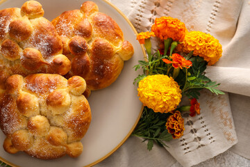 Plate with bread of the dead and marigold flowers on grunge background. Celebration of Mexico's Day of the Dead (El Dia de Muertos)