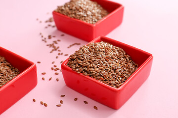 Bowls with flax seeds on color background, closeup