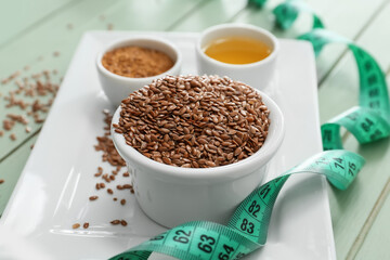 Bowl with flax seeds and measuring tape on table, closeup