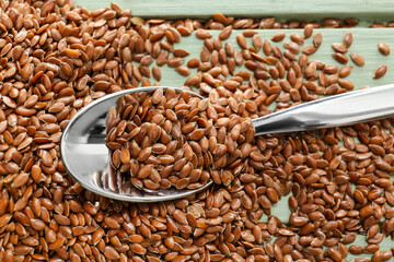 Spoon with flax seeds on color wooden background, closeup