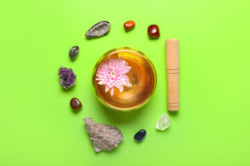 Tibetan singing bowl and chakra stones on color background