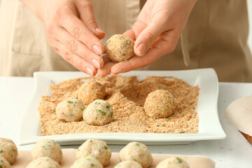 Woman cooking cod cutlets at table, closeup