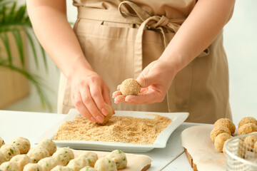 Woman cooking cod cutlets at table