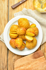 Plate with tasty baked potato on wooden background