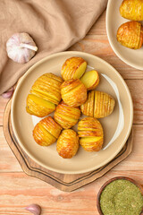 Plate with tasty baked potato on wooden background