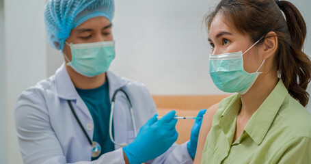 Doctors wearing protective clothing and masks are vaccinating. Doctor holding syringe and using cotton before make injection to patient in medical mask. Covid-19 or coronavirus vaccine.