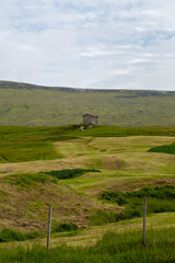 Obraz premium Beautiful aerial view of a traditional lonely house -barn in the middle of the mountains in the Faroe Islands