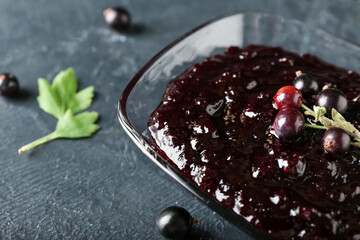 Bowl with black currant jam on dark background