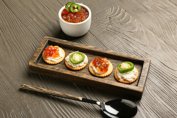 Fototapeta na wymiar Delicious crackers with cottage cheese and jalapeno pepper jam on grey wooden table
