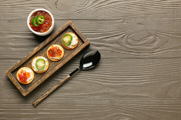 Delicious crackers with cottage cheese and jalapeno pepper jam on grey wooden table