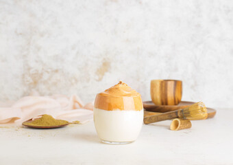 Glass of tasty dalgona hojicha latte on light background