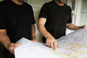 Team members pointing at architectural drawing and problem solving at construction site