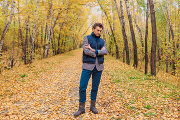 Tall handsome man walking in the autumn alley