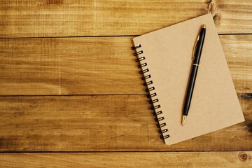 Notebook placed on a brown wooden floor and a pen