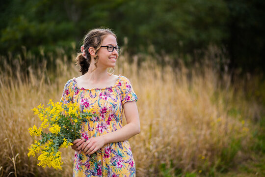 Young woman with bouquet of wattle blossoms outside in nature
