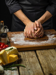 The chef prepares the dough for making focaccia, pizza, pie, pasta. Cheese, tomatoes, olive oil, spices - ingredients. Careful viewing. Recipe book, step by step recipe.