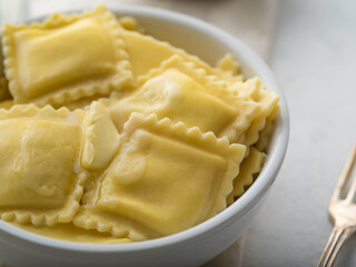 Large white bowl with delicious Italian ravioli drizzled with butter. Macro photography. Careful viewing. White background. Home cooking, family lunch, restaurant, hotel, cafe, food design.