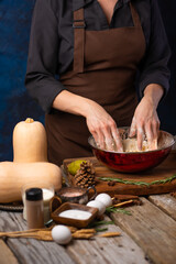 The chef kneads the dough for a festive pumpkin pie. Beautiful composition - many ingredients and decor. Thanksgiving, Halloween, New Years, Christmas, family holidays.