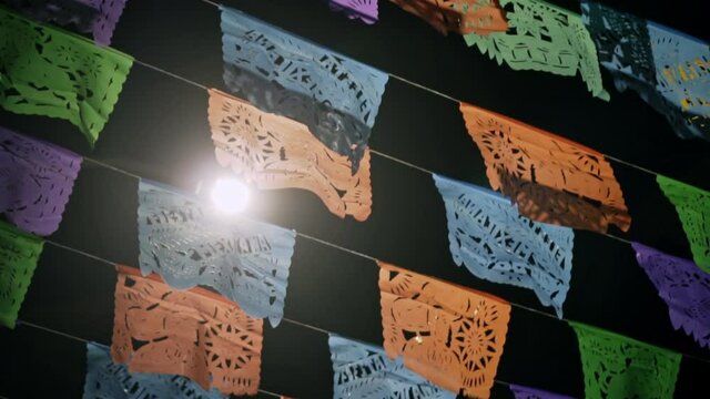 Panning down long line of Papel Picado perforated paper mexican flags at night