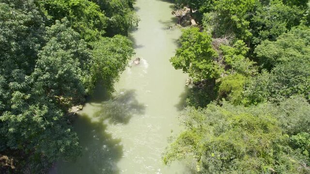 Drone aerial footage of flowing rainforest river lined with green lush trees. Guatemalan river Rio Cahabon near Semuc Champey, Guatemala. Daytime.
