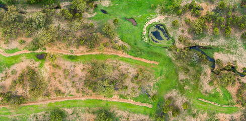 Erosion prevention embankments and creek flowing to dam in paddock with new green growth