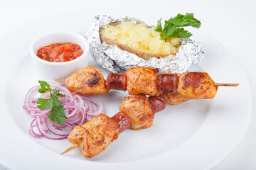 chicken skewers with baked potatoes and spicy sauce with onions