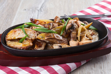 Italian frying pan with potatoes, meat and mushrooms in mushroom sauce