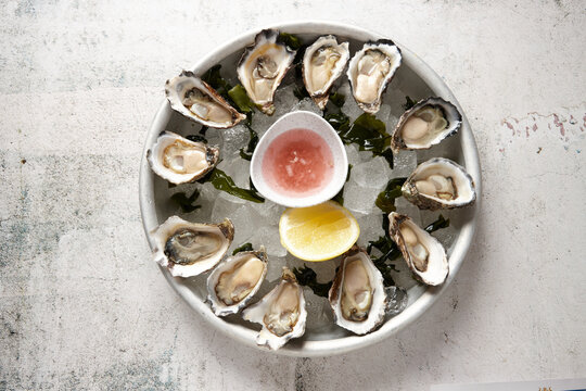 top view shot of fresh oyster seafood platter on top of ice cubs with bowls of sauce