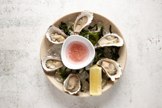 top view shot of fresh oyster seafood platter on top of ice cubs with bowls of sauce