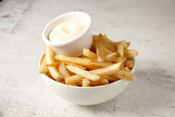 close up shot of a white bowl of potato fries with mayo dip