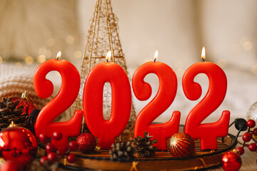 Happy New Years 2022. Numbers of year 2022 made by red candles on bokeh festive sparkling...
