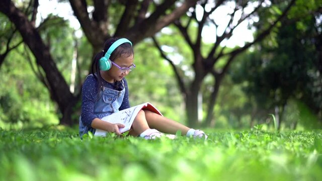 Slow motion Happy asian little child girl reading a book in the garden