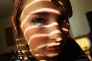 Close up dramatic light and shadows fall on attractive woman's face up-close