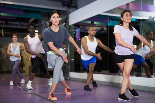 Multiethnic group of adult people practicing active dancing in class at fitness center