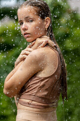Fototapeta na wymiar Girl in the rain. Young beautiful girl with splashing water. High quality photo