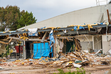 Horizontal shot of a partly demolished house with wood waste scraps and building material