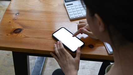 Obraz premium Cropped shot businesswoman using smart phone while sitting at office desk.